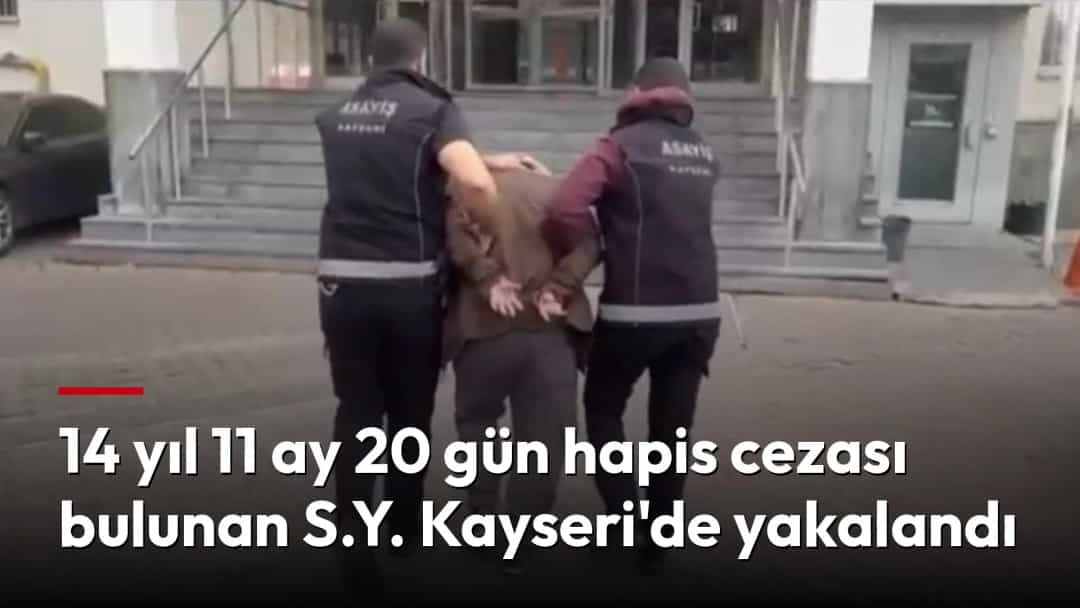 Polis ekipleri, elleri kelepçeli bir kişiyi emniyet binasının önünde götürüyor.