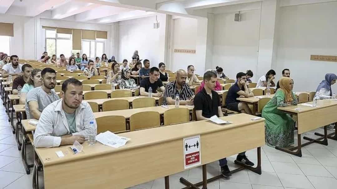 Adaylar, sınıf ortamında sınav sorularını yanıtlarken.