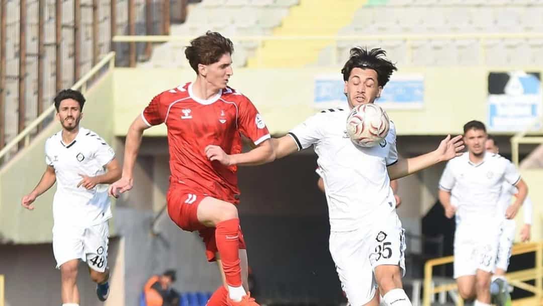 Altaylı kırmızı formalı futbolcu ile 1922 Akşehir SK'lı beyaz formalı futbolcu, maç sırasında top için mücadele ediyor.