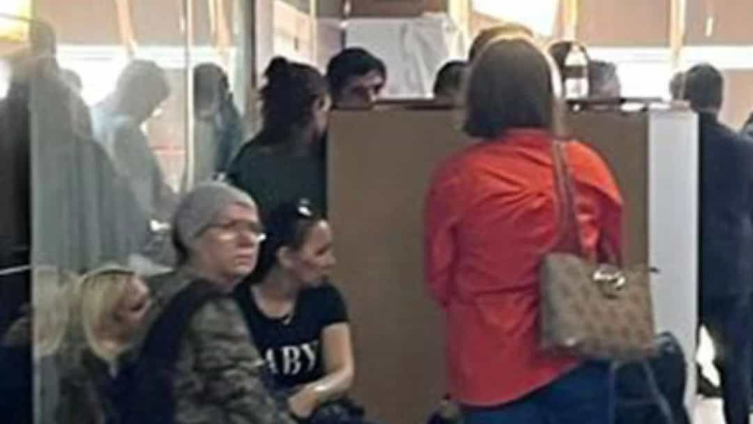 Kapalı bir alanda çevresinde insanlar bulunan bir polis memuru