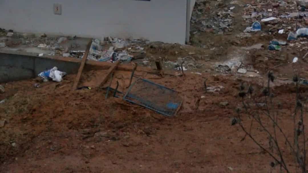 Çamurla kaplı, çöplerin ve devrilmiş parçaların bulunduğu bir alan.