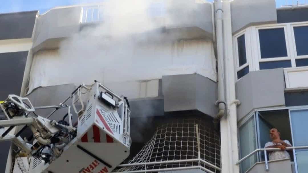 Muratpaşa'da bir binanın çatısından yükselen dumanı itfaiye ekipleri merdivenli araçla söndürüyor.