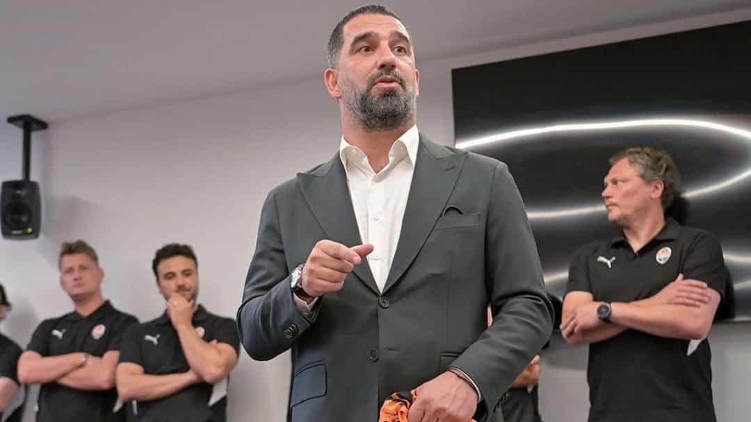 Arda Turan, koyu renk takım elbise ve beyaz gömlekle bir açıklama yaparken.
