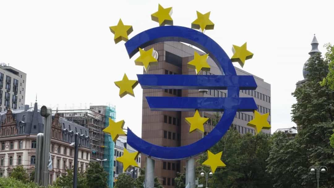 Avrupa’daki bir binanın önünde yer alan yıldızlarla çevrili büyük mavi euro simgesi.