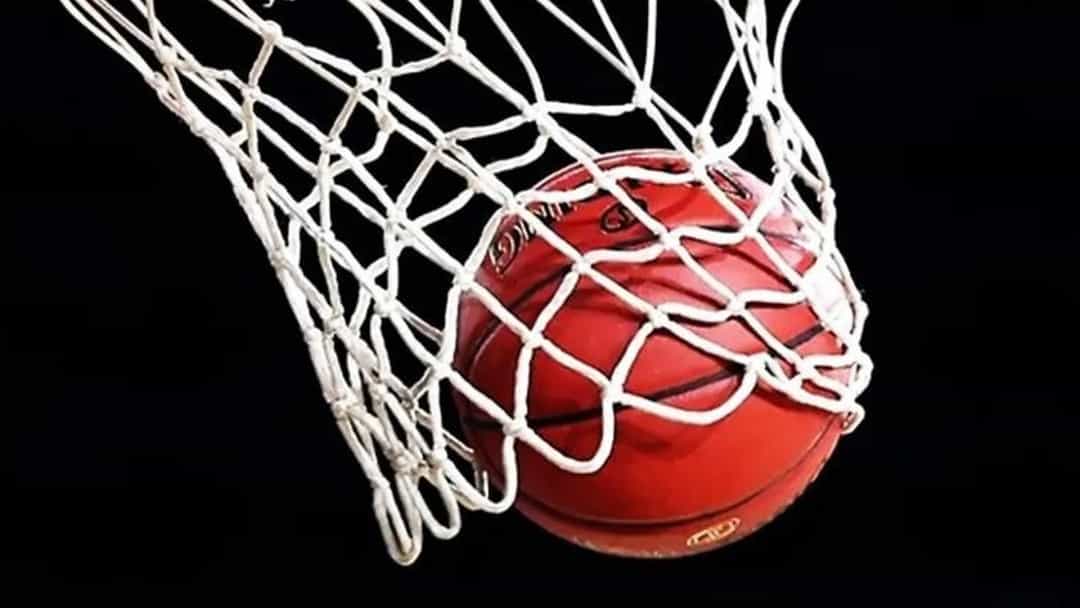 Turuncu çemberden geçen basketbol topu ve file.