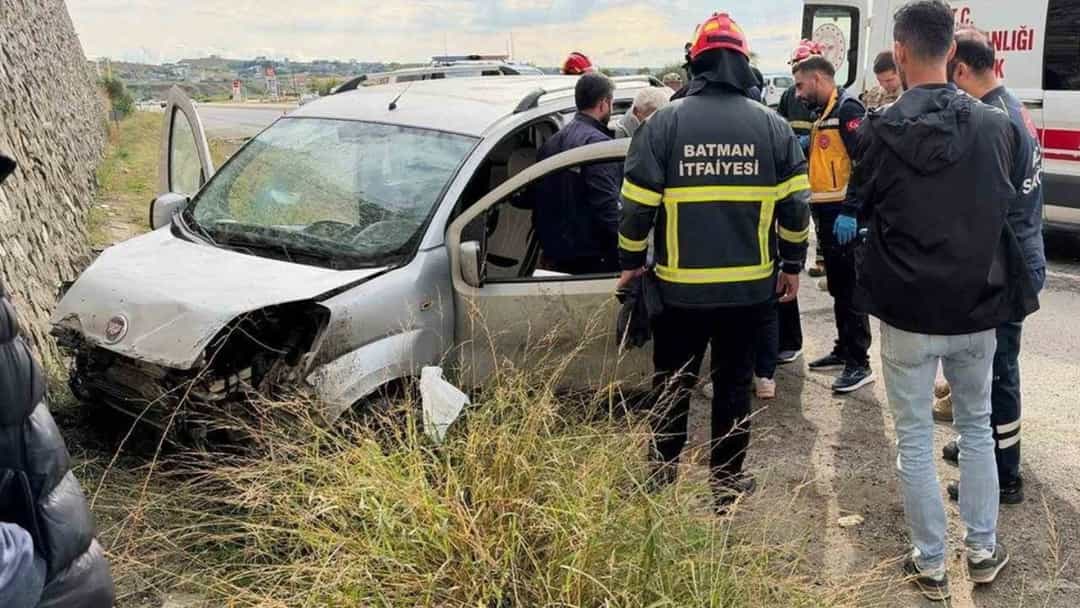 Duvara çarpan otomobilin yanında itfaiye ekipleri ve sağlık görevlileri inceleme yapıyor.