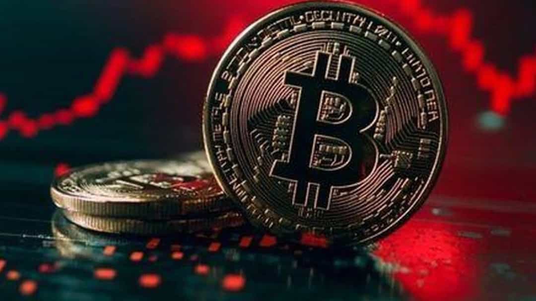 Kırmızı düşüş grafiği önünde duran Bitcoin temalı madeni para.
