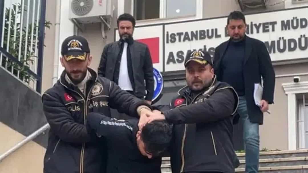 Polis ekipleri, yüzü görünmeyen şüpheliyi bir binanın merdivenlerinden indiriyor.