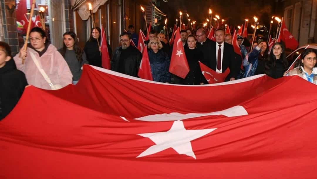 Gece düzenlenen fener alayında kalabalık, büyük bir Türk bayrağı taşıyarak sokakta ilerliyor.