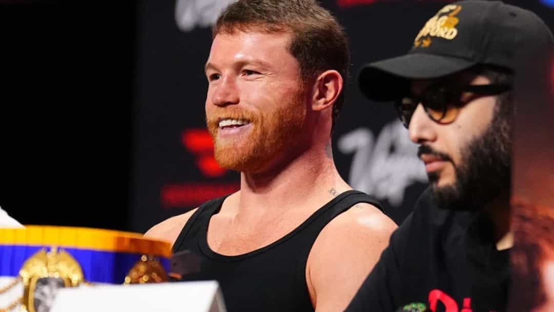 Canelo Alvarez, basın toplantısında siyah kolsuz üstüyle gülümserken.