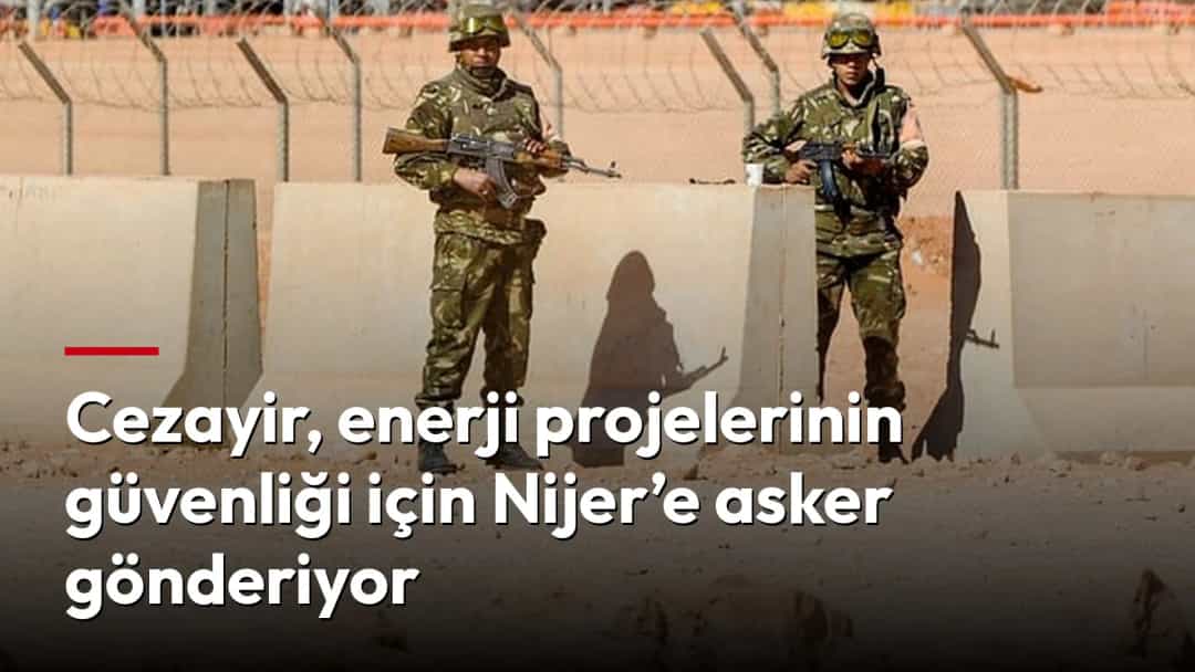 İki asker, çöl bölgesindeki enerji tesisini çevreleyen güvenlik duvarının önünde nöbet tutuyor.