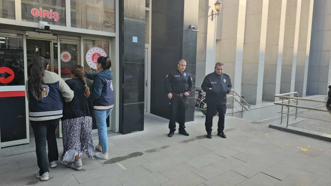 Polis ekipleri, binanın girişinde bulunan kişilere eşlik ediyor.