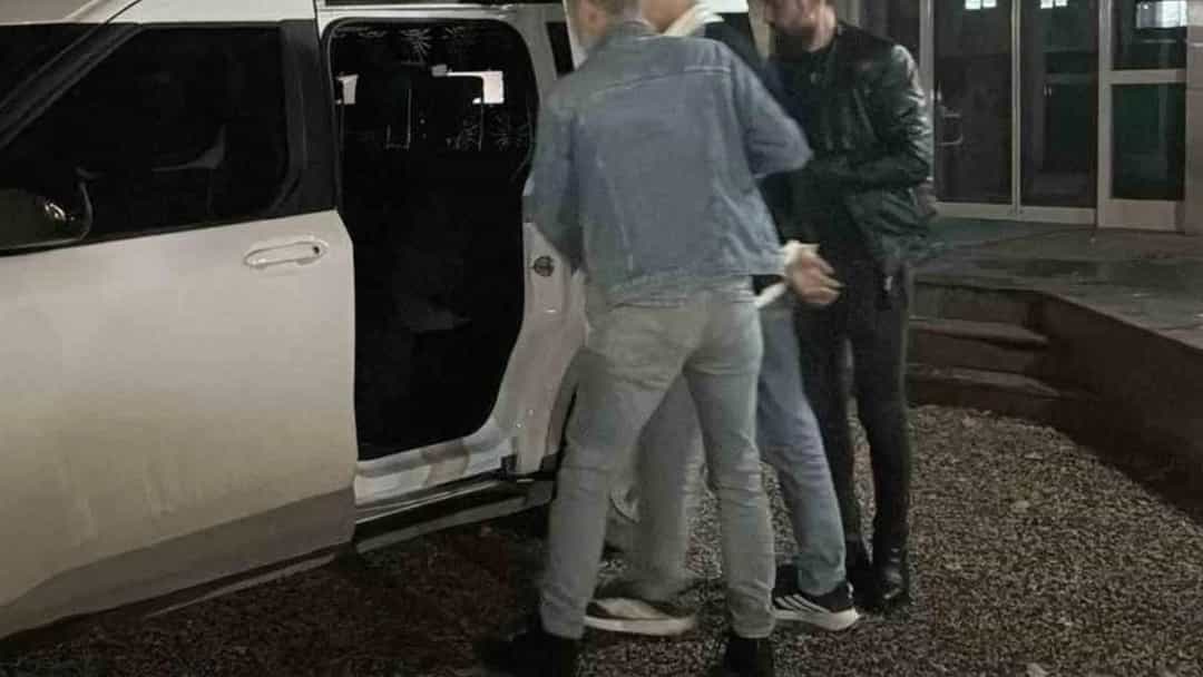 Gece saatlerinde açık kapılı bir aracın yanında duran üç kişi
