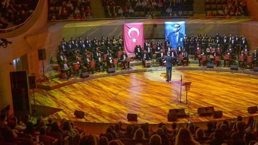 Türk bayrağı ve Atatürk portresinin yer aldığı konser salonunda sahne alan orkestra