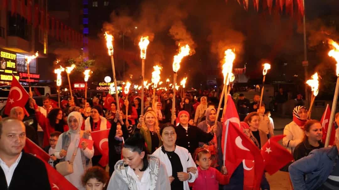 Cumhuriyet kutlamalarında ellerinde meşaleler ve Türk bayrakları taşıyan kalabalık gece yürüyüşünde.