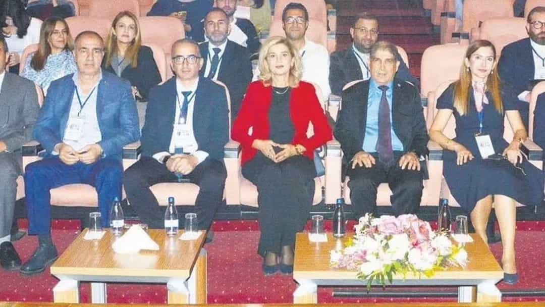 Bir sempozyum salonunda ön sıralarda oturan katılımcılar ve arkalarındaki dinleyiciler