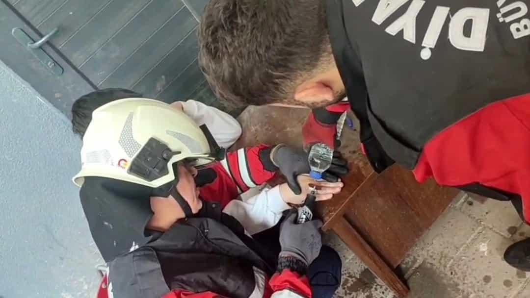 İtfaiye erleri, çocuğun parmağına sıkışan metali keserek çıkarmak için çalışıyor.