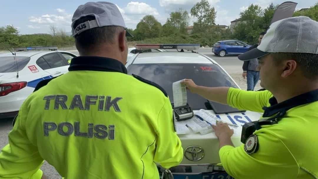 Trafik polisleri park halindeki bir aracın yanında evrakları inceliyor.