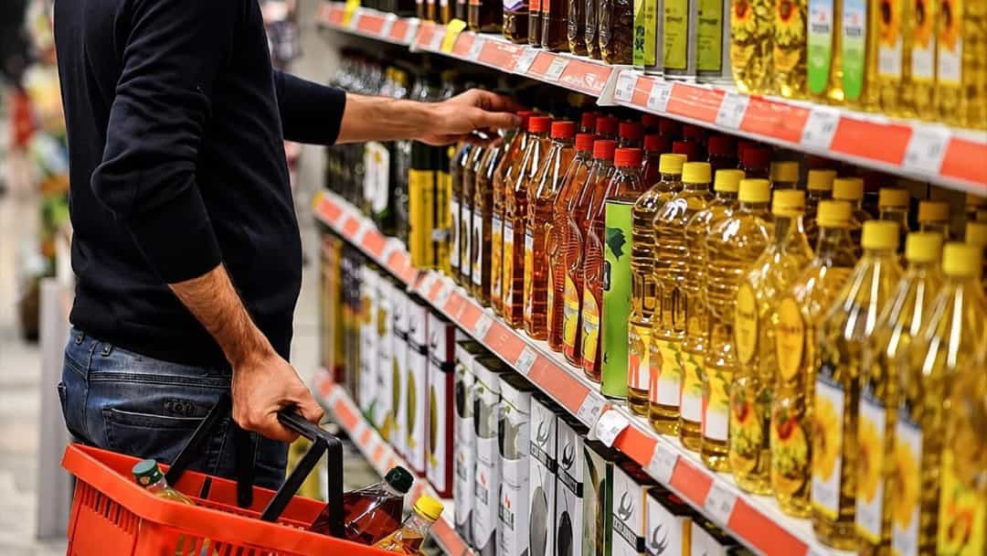Bir kişi market rafındaki yağ ürünlerini inceliyor.
