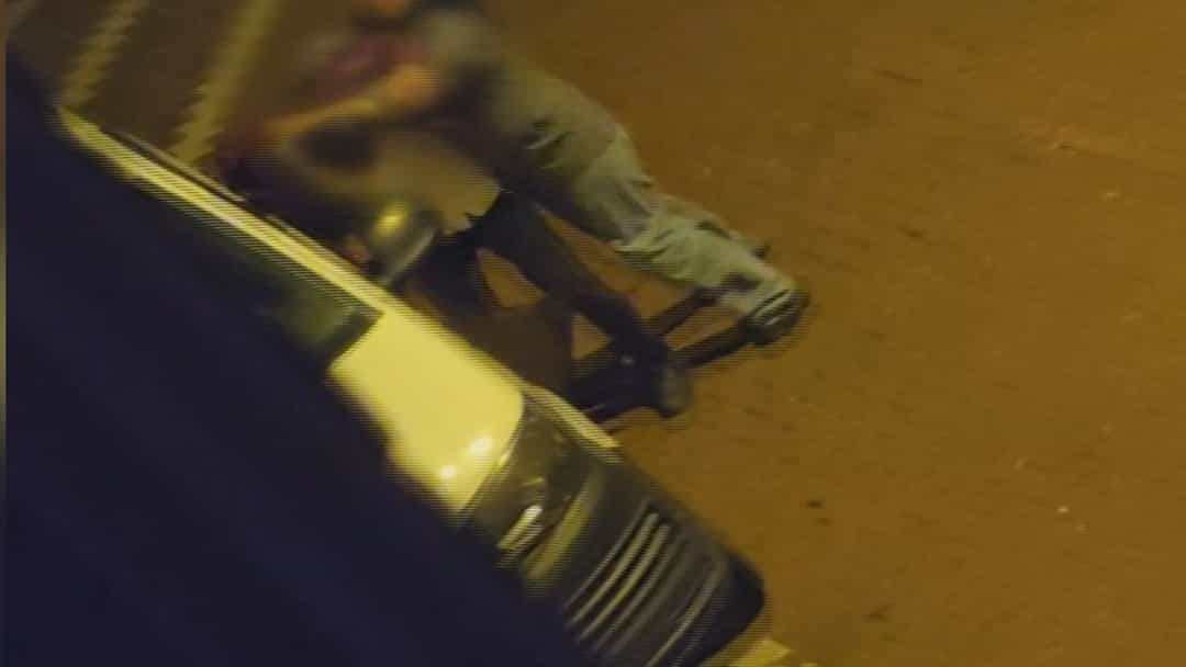 Gece saatlerinde park halindeki araçların yanında iki kişi yerde boğuşuyor.