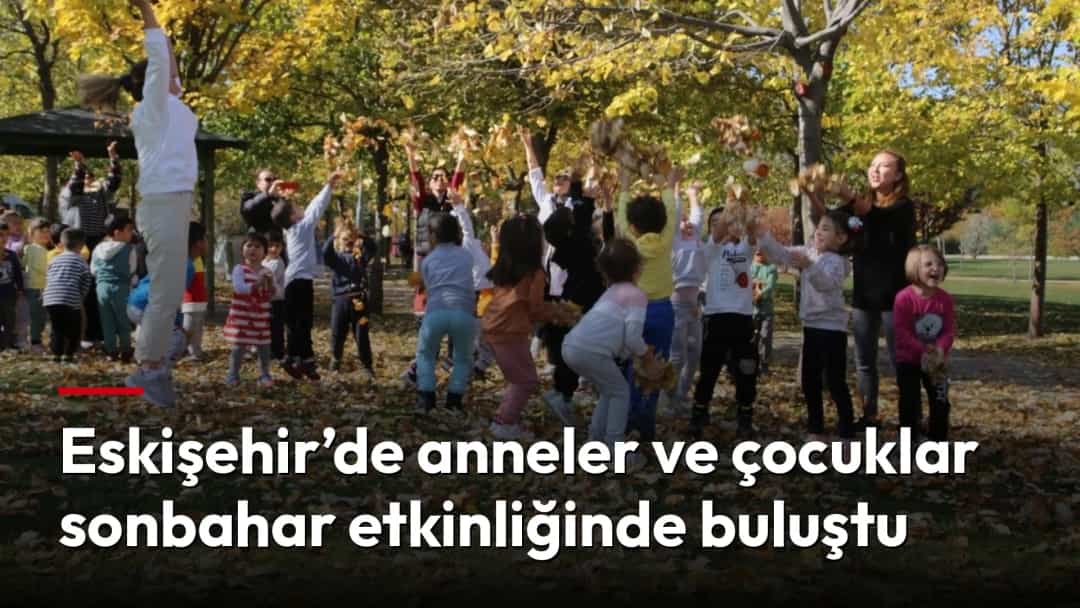 Çocuklar sonbahar yapraklarıyla kaplı bir parkta anneleriyle birlikte etkinliğe katılıyor.