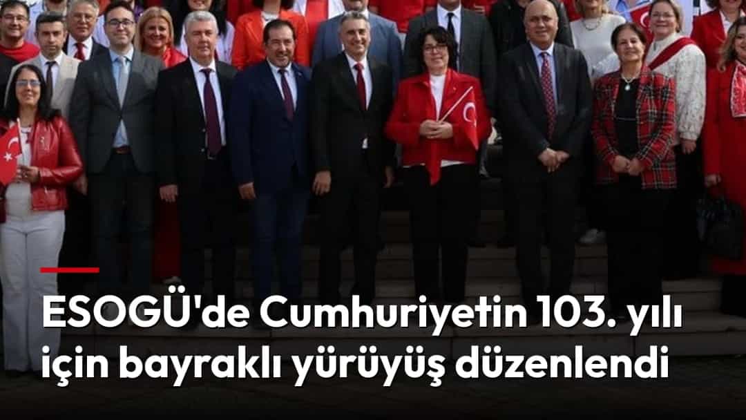 Türk bayrakları taşıyan kalabalık, bir anıtın önünde toplu fotoğraf çektiriyor.