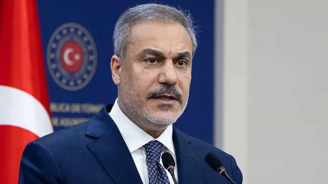 Hakan Fidan, Türk bayrağı ve bakanlık ambleminin önünde konuşurken.