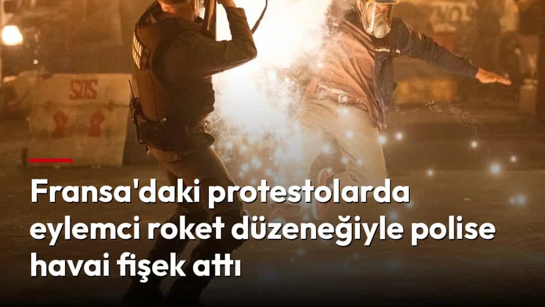 Gece düzenlenen protestoda bir eylemci, karşısındaki kişiye doğru havai fişek fırlatan bir düzenek tutuyor.