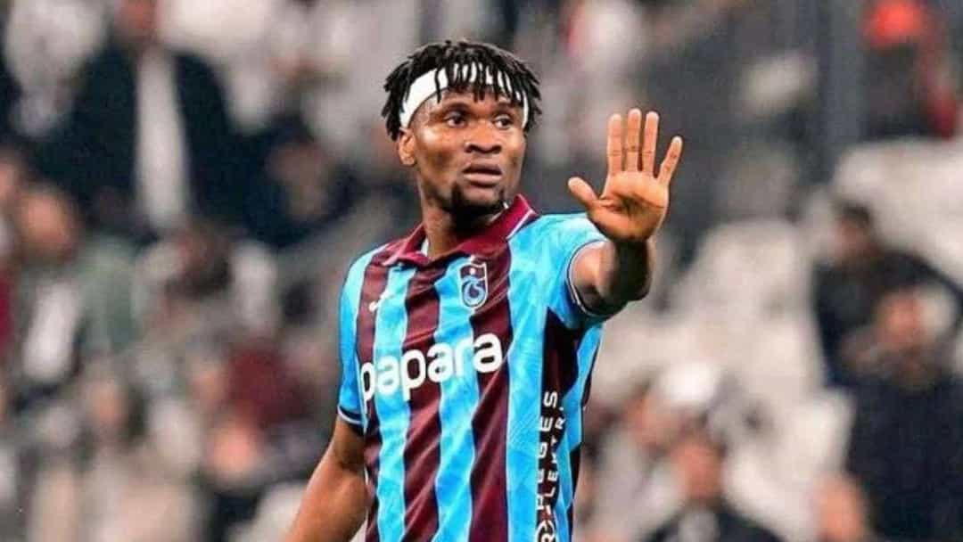 Trabzonspor forması giyen Chibuike Nwaiwu, tribünlerin önünde elini kaldırıyor.