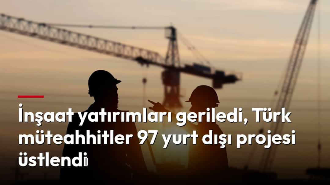 Gün batımında vinçlerin önünde konuşan iki inşaat işçisi.