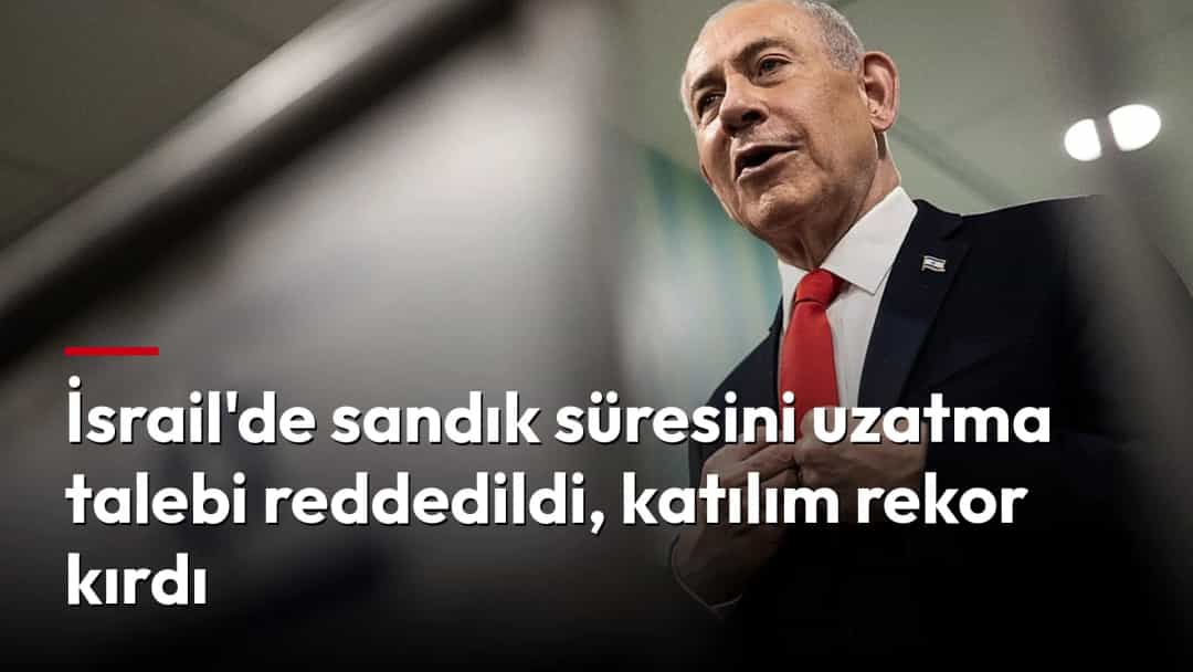 Benjamin Netanyahu konuşurken ceketini düzeltirken, ön planda İsrail bayrağı bulanık şekilde görülüyor.