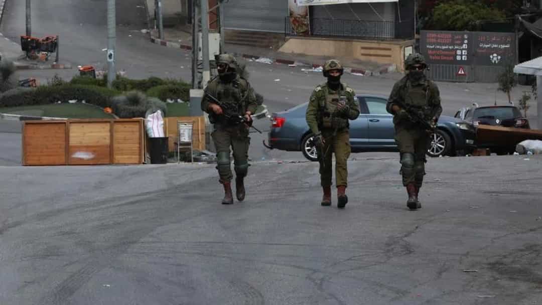 Bir sokakta devriye gezen İsrail askerleri ve askeri araç.