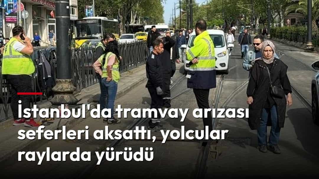 Tramvay seferlerinin aksaması nedeniyle yolcular rayların üzerinden yürürken görevliler çevredeki trafiği yönlendiriyor.