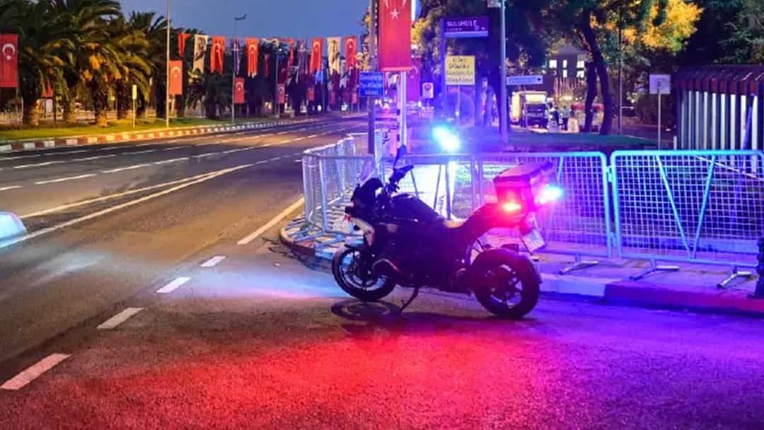 Gece saatlerinde bariyerlerle trafiğe kapatılmış bir yol ve ışıkları yanan polis motosikleti.