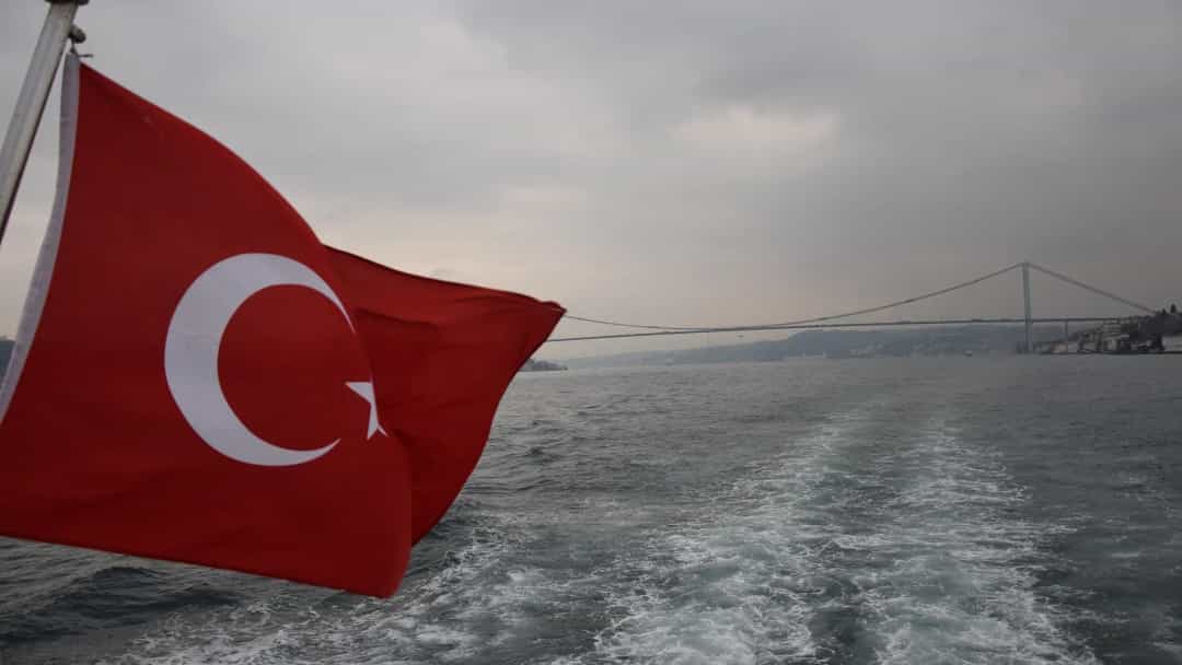 İstanbul Boğazı'nda bir teknenin arkasında dalgalanan Türk bayrağı ve Boğaz köprüsü