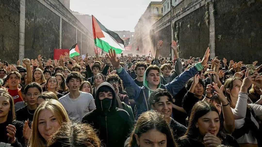 Dar bir sokakta toplanan kalabalık, Filistin bayrakları taşıyarak protesto gösterisi yapıyor.