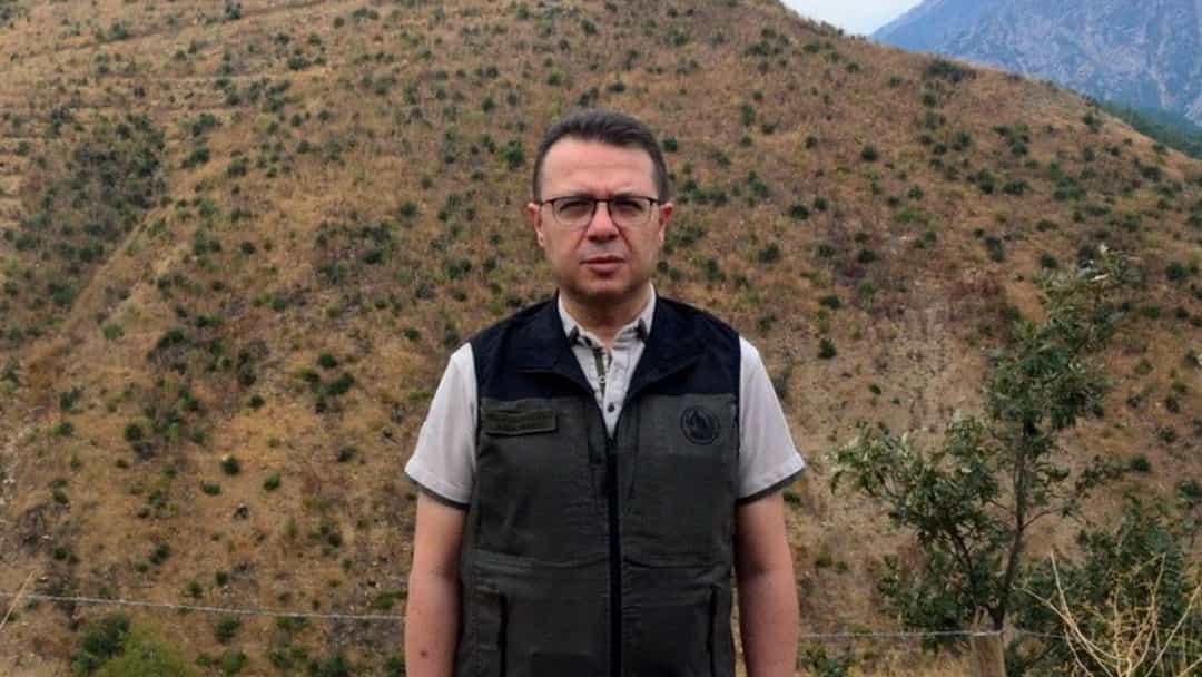 Bir yetkili, Kahramanmaraş'ta ağaçlandırma çalışması yapılan seyrek bitki örtülü yamaç önünde duruyor.