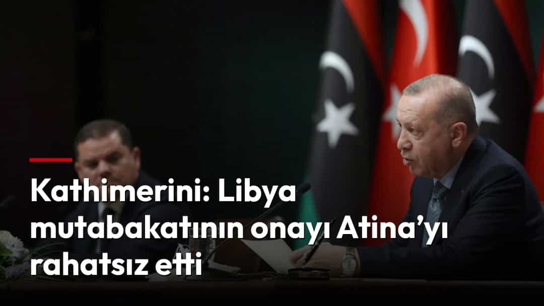 Recep Tayyip Erdoğan, Türkiye ve Libya bayraklarının önünde bir toplantı masasında oturuyor.