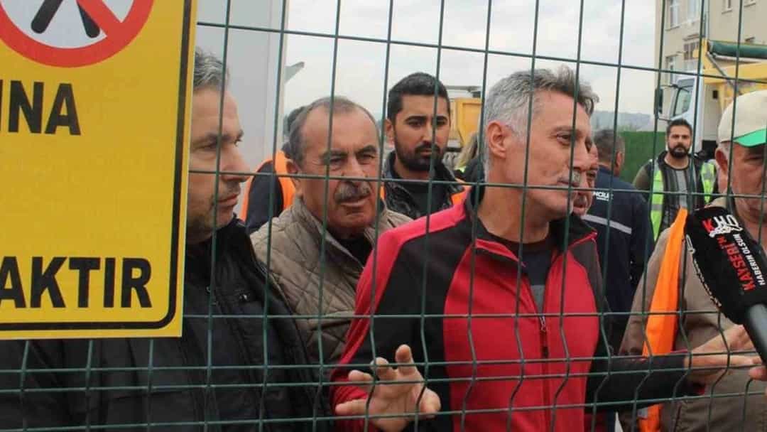 Kayseri'de iş bırakan işçiler, bir güvenlik telinin arkasında basın mensuplarına konuşuyor.