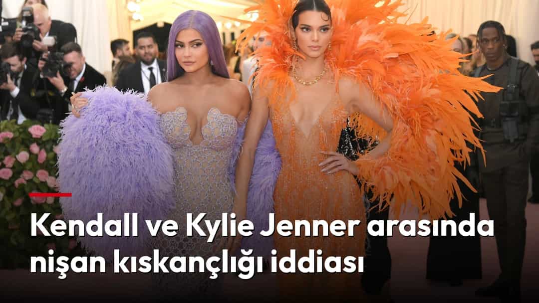 Kendall Jenner, turuncu tüylü elbisesiyle kız kardeşi Kylie Jenner’ın yanında bir etkinlikte poz veriyor.