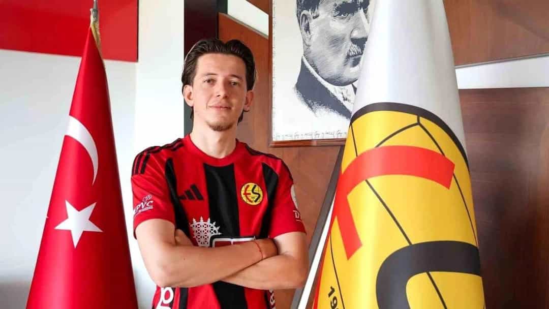 Kerem Baykuş, Eskişehirspor formasıyla kulüp bayraklarının arasında poz veriyor.