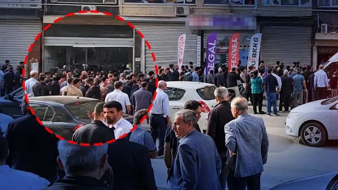 Bir iş hanının önünde toplanan kalabalık ve binanın önünde bekleyen acil durum araçları.