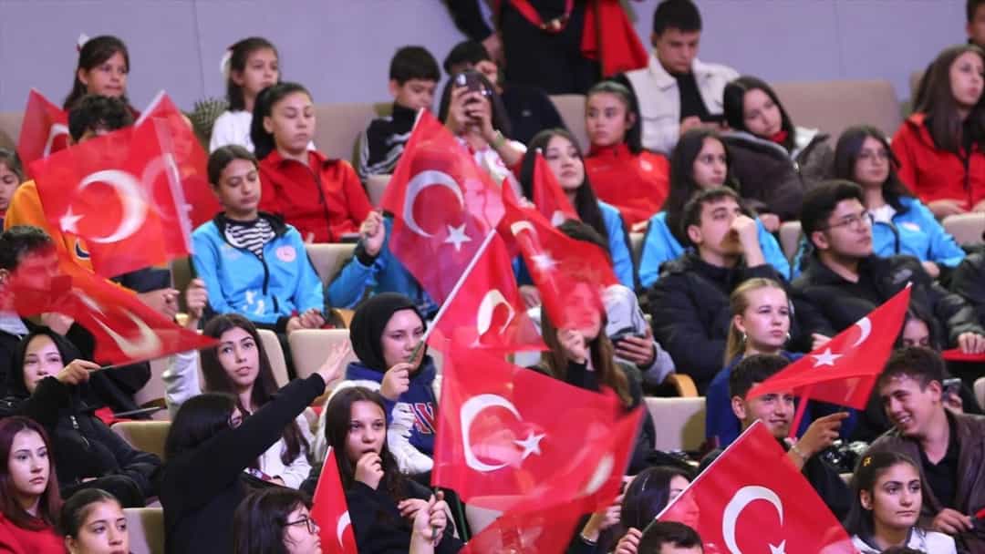 Cumhuriyet Bayramı etkinliğini izleyen kalabalık, Türk bayrakları sallıyor.