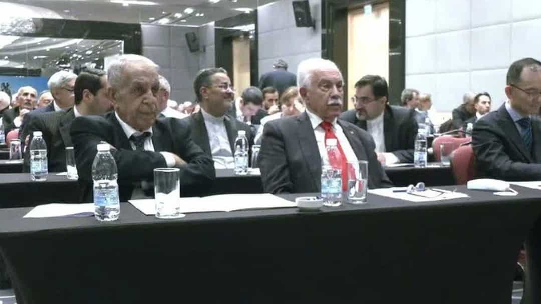Bülent Kuşoğlu, konferans salonunda katılımcılarla birlikte masada oturuyor.