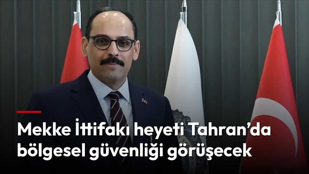 İbrahim Kalın, Türk bayrakları ve kurum bayrağının önünde poz veriyor.