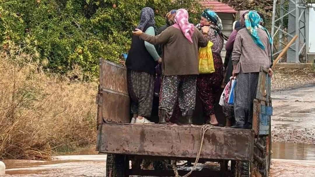 Sağanak sonrası su basan seraların önünde, römork üzerinde taşınan kadınlar