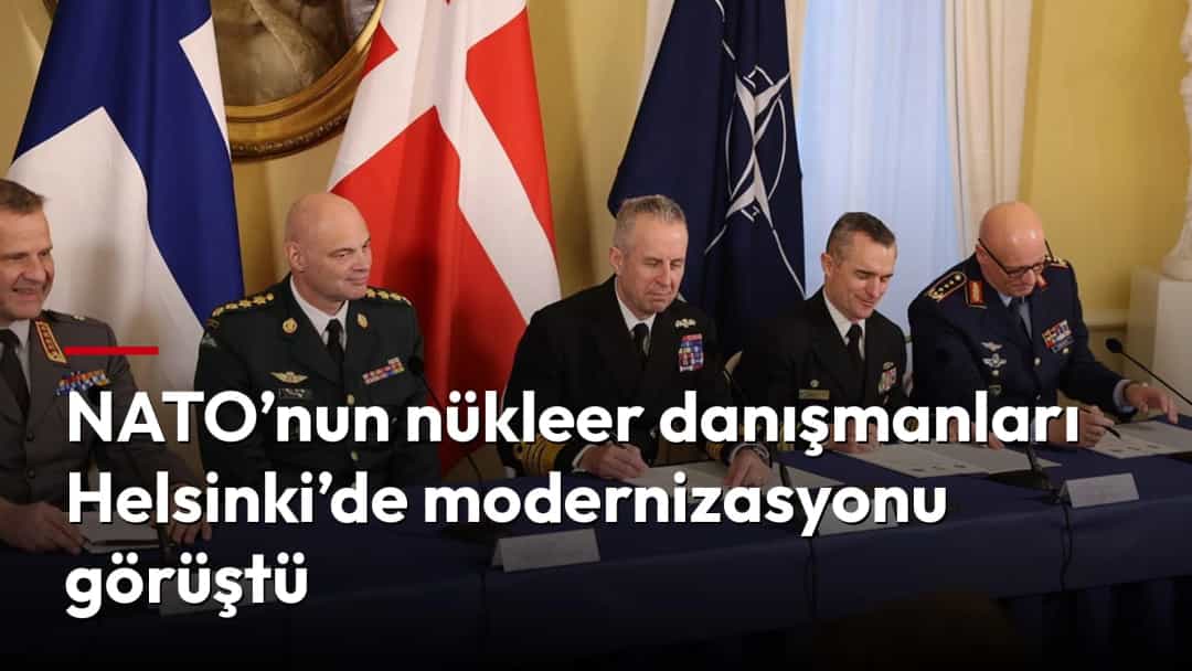 NATO ve üye ülke bayrakları önünde bir toplantı masasında oturan askerî yetkililer belgeleri inceliyor.