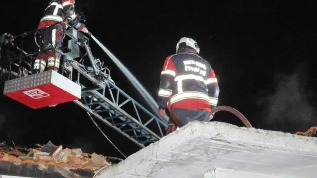 İtfaiyeciler merdivenli araçla evin çatısındaki yangına müdahale ediyor.