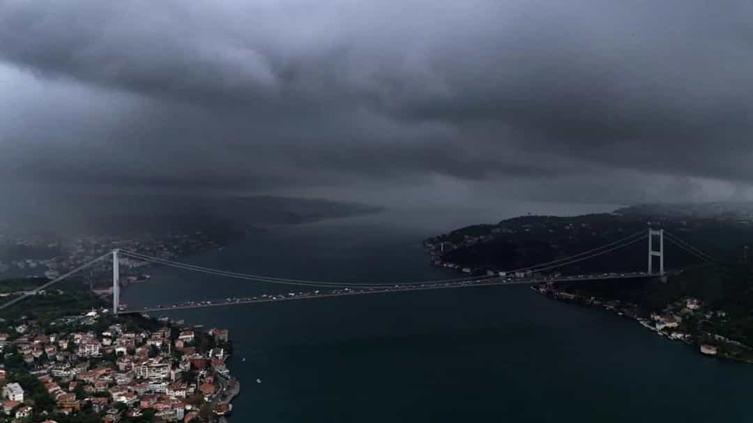 Koyu yağmur bulutları altında, köprü ve çevresindeki yerleşim alanının havadan görünümü.