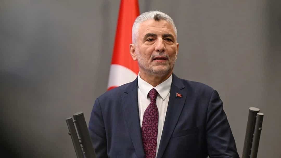 Ömer Bolat, Türk bayrağı önünde kürsüde konuşurken.